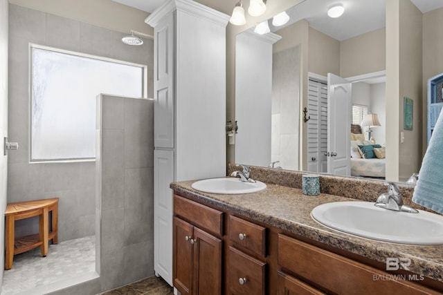 bathroom with a tile shower, tile patterned flooring, and vanity