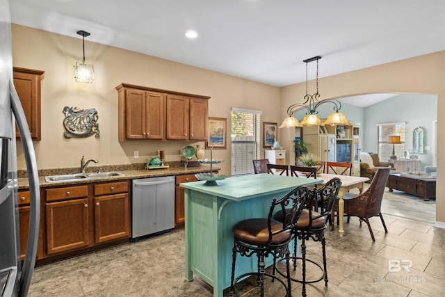 kitchen with a kitchen bar, stainless steel dishwasher, sink, decorative light fixtures, and a center island