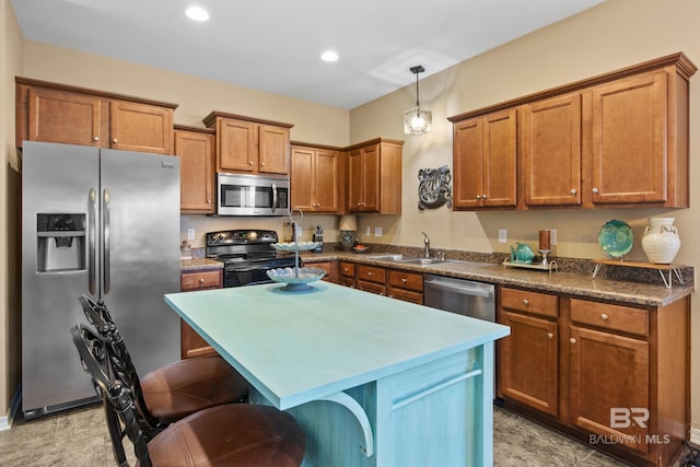 kitchen with stainless steel appliances, sink, pendant lighting, a kitchen island, and a breakfast bar area