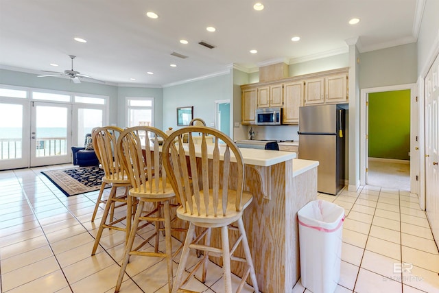 310 Audubon Pl, Dauphin Island, AL 36528 - kitchen featuring stainless steel appliances, light brown cabinetry, light countertops, an island with sink, and light tile patterned floors