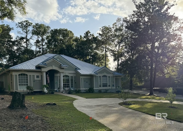 ranch-style home with metal roof, a front yard, and a standing seam roof