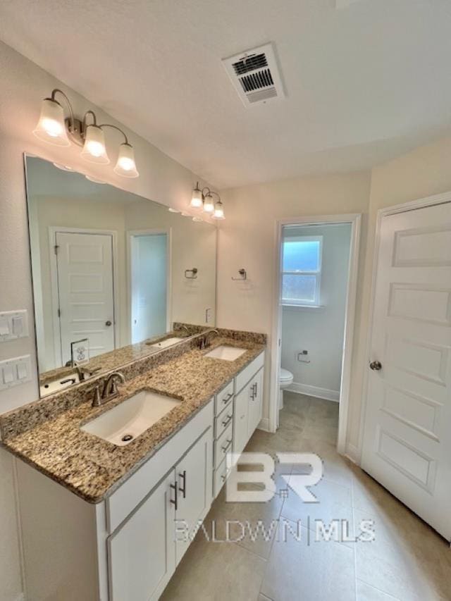 bathroom with tile patterned flooring, vanity, and toilet