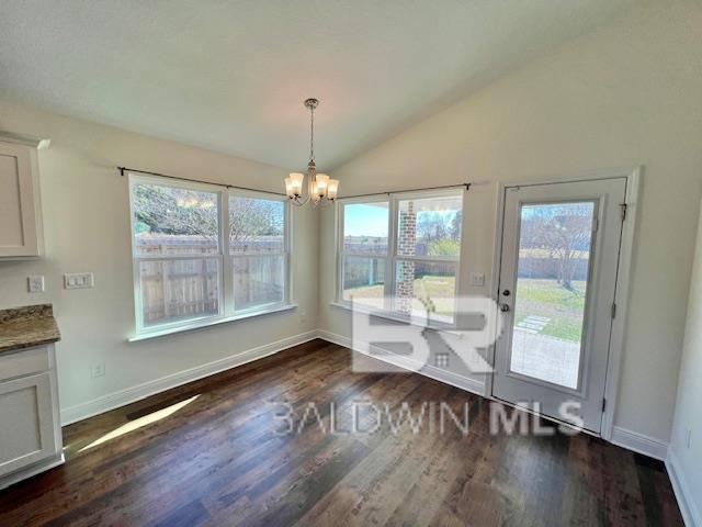 unfurnished dining area with a chandelier, vaulted ceiling, and dark wood-type flooring