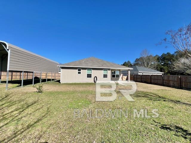 back of property with a lawn and a carport