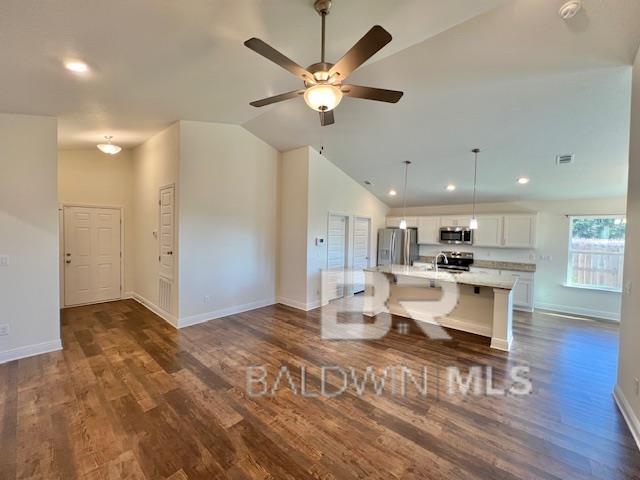 kitchen featuring light stone countertops, an island with sink, a breakfast bar, white cabinets, and appliances with stainless steel finishes