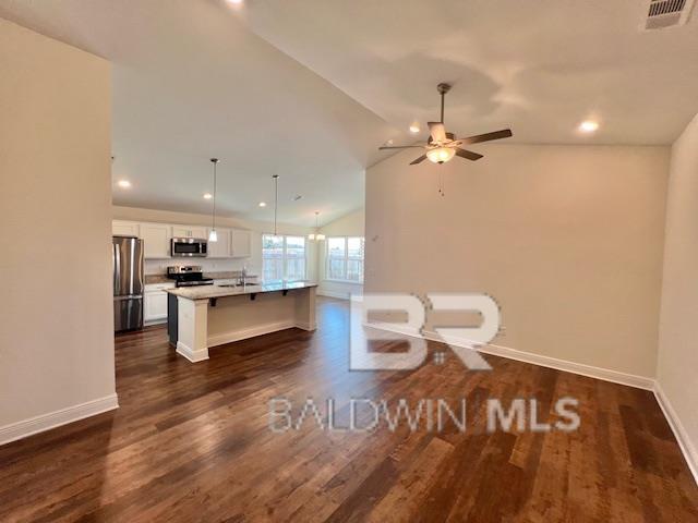 kitchen with hanging light fixtures, stainless steel appliances, lofted ceiling, a breakfast bar, and a center island with sink