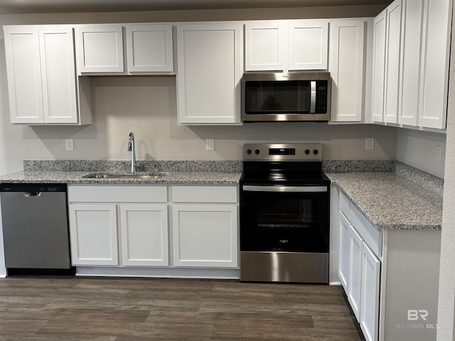 13710 Logan Pl, Foley, AL 36535 - kitchen with stainless steel appliances, a sink, white cabinetry, light stone countertops, and dark wood finished floors