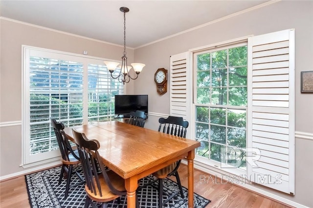 dining area with a notable chandelier, light hardwood / wood-style flooring, and crown molding