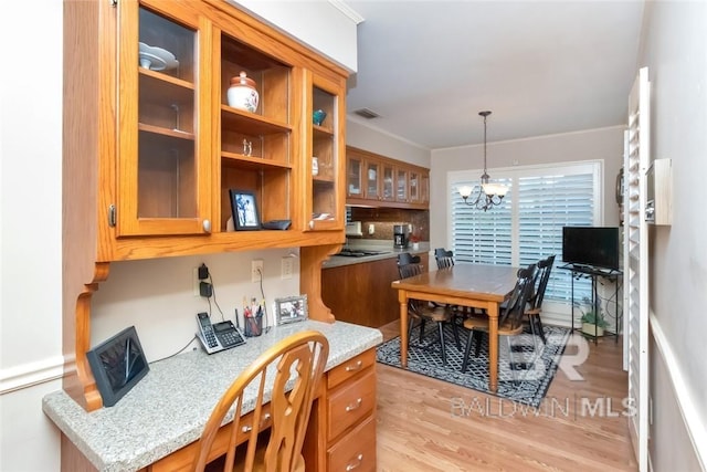 kitchen featuring light hardwood / wood-style flooring, light stone counters, pendant lighting, and a chandelier