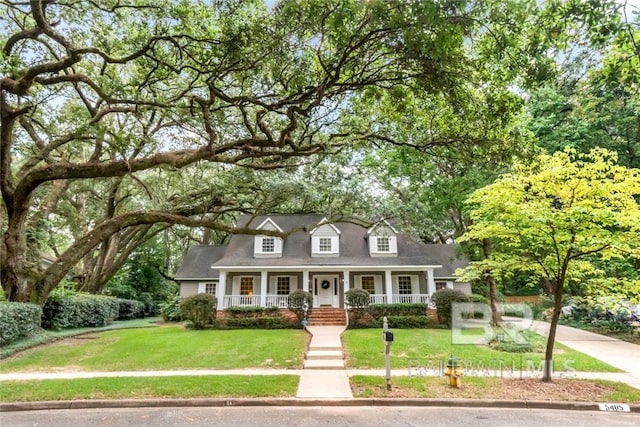 cape cod home featuring a front lawn and covered porch