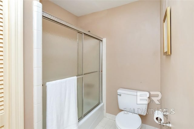 bathroom with tile patterned flooring, toilet, and bath / shower combo with glass door