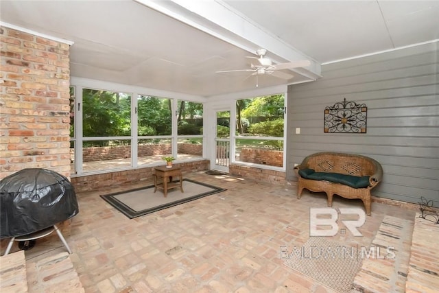 sunroom / solarium featuring ceiling fan and beamed ceiling