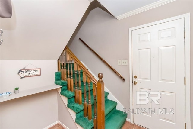 stairway with crown molding and wood-type flooring