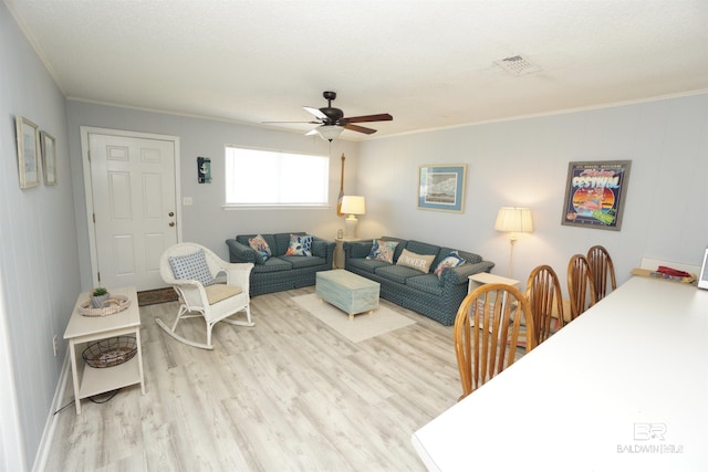 living room with crown molding, a ceiling fan, visible vents, and wood finished floors