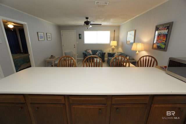 kitchen featuring stainless steel microwave, crown molding, visible vents, ceiling fan, and light countertops