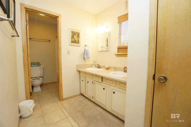 bathroom featuring toilet, tile patterned flooring, a sink, and double vanity
