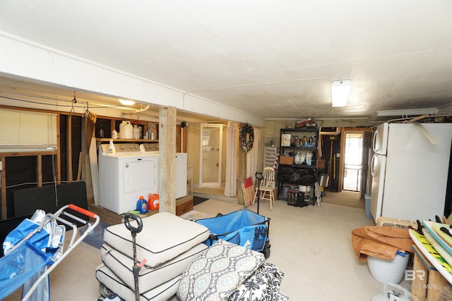 below grade area featuring washer and dryer and freestanding refrigerator
