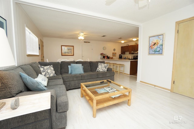 living room with light wood-type flooring and a ceiling fan