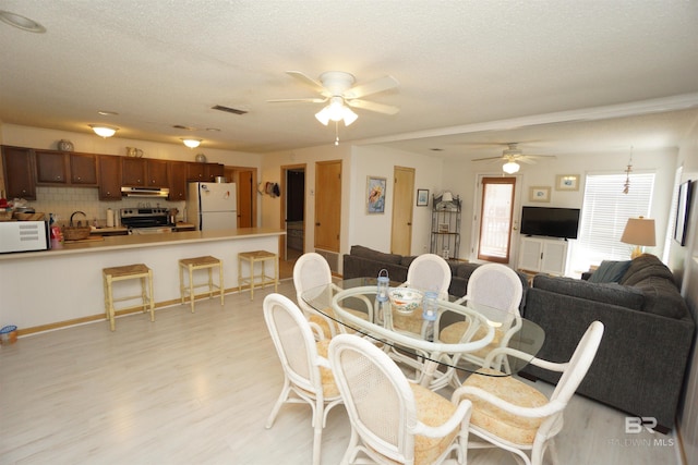 dining area with visible vents, ceiling fan, a textured ceiling, and light wood finished floors