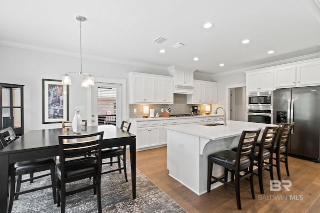 kitchen featuring appliances with stainless steel finishes, dark hardwood / wood-style floors, a center island with sink, and sink