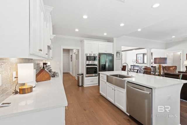 kitchen featuring wood-type flooring, tasteful backsplash, sink, appliances with stainless steel finishes, and a kitchen island with sink