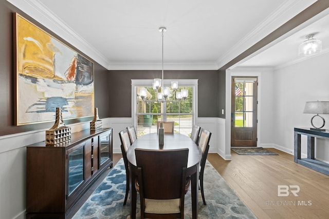 dining space featuring crown molding, hardwood / wood-style floors, and an inviting chandelier