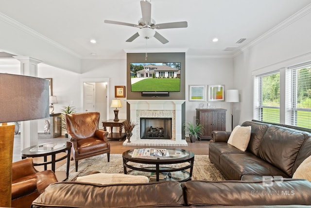 living room with a fireplace, crown molding, ornate columns, ceiling fan, and wood-type flooring