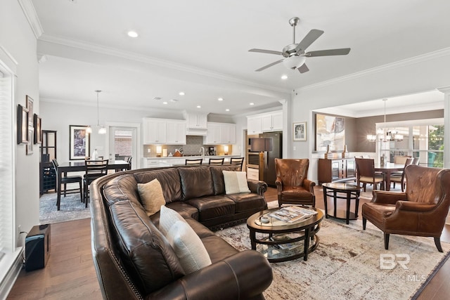 living room featuring ornamental molding, ceiling fan with notable chandelier, and hardwood / wood-style floors