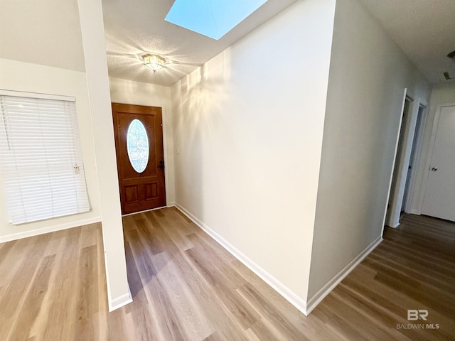 entrance foyer featuring a textured ceiling, hardwood / wood-style flooring, and a skylight