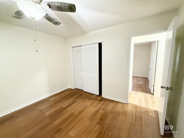 unfurnished bedroom featuring ceiling fan, wood-type flooring, and a closet