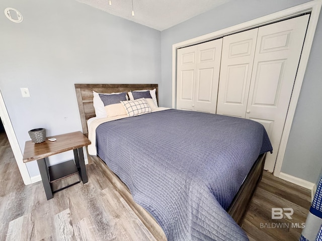 bedroom featuring a closet, wood finished floors, and baseboards