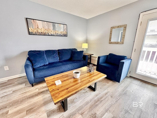 living area with baseboards, light wood-style flooring, and a textured ceiling