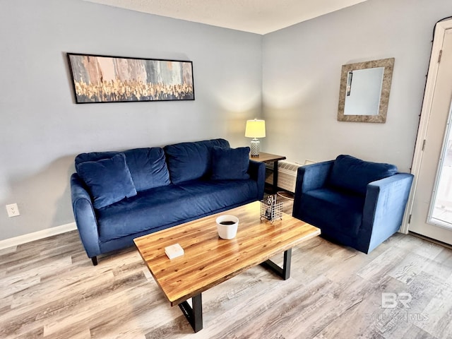 living room featuring an AC wall unit, wood finished floors, and baseboards