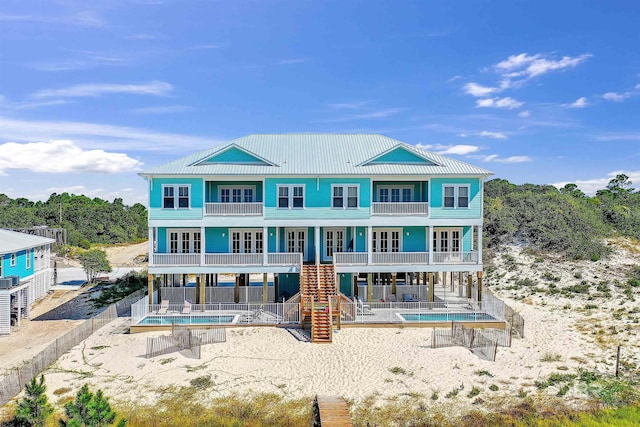 back of property featuring stairs, french doors, a patio area, and a balcony