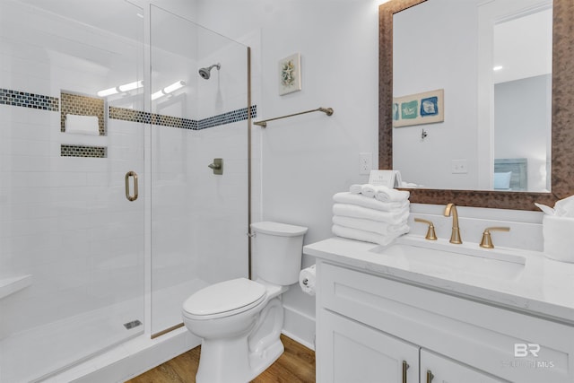 full bath featuring vanity, a shower stall, toilet, and wood finished floors