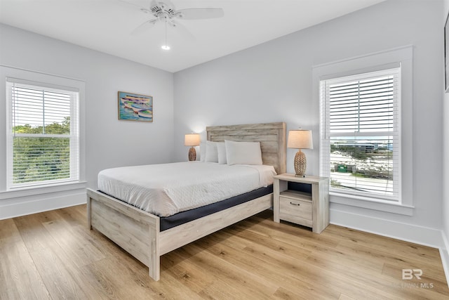 bedroom with light wood-style floors, ceiling fan, and baseboards