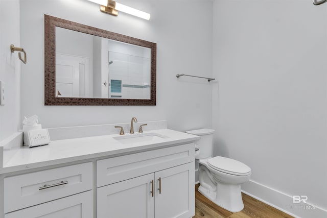 full bathroom featuring toilet, wood finished floors, vanity, baseboards, and walk in shower