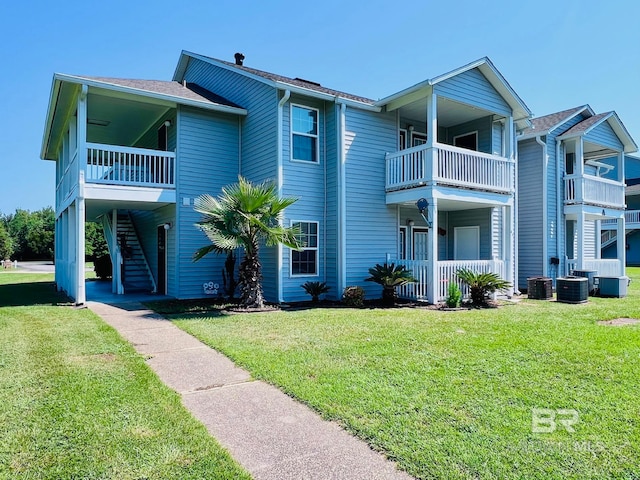 view of front of property featuring a balcony, a front yard, and central air condition unit