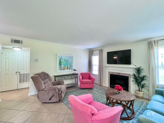 living room featuring a tiled fireplace, light tile patterned flooring, and crown molding