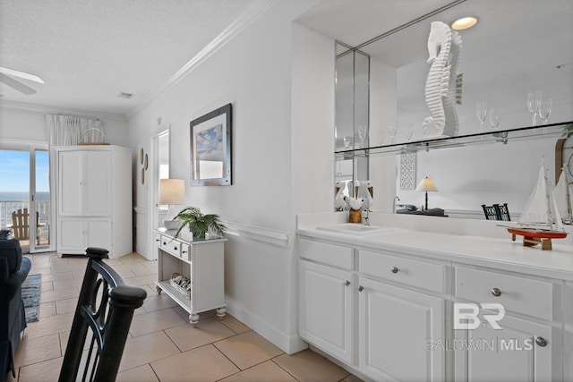 kitchen featuring white cabinetry, light tile floors, ceiling fan, a textured ceiling, and ornamental molding