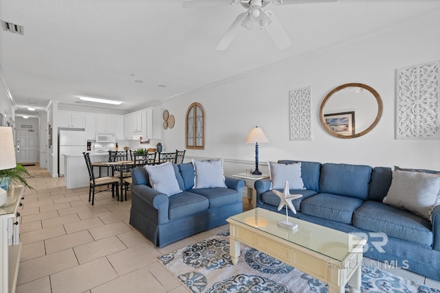 tiled living room with ceiling fan and crown molding