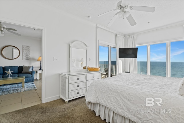 bedroom with dark tile floors, a textured ceiling, ceiling fan, and a water view