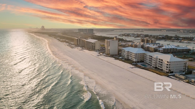 aerial view at dusk with a water view and a view of the beach