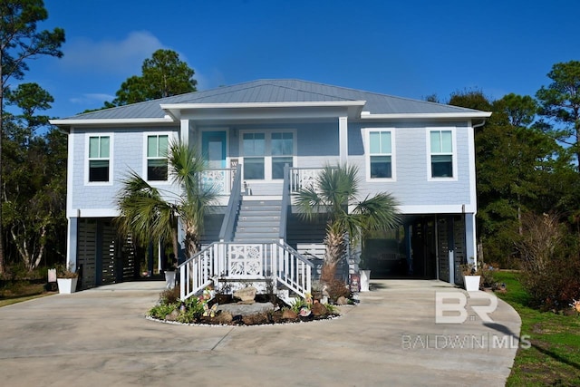 coastal home with a carport, concrete driveway, covered porch, and stairway