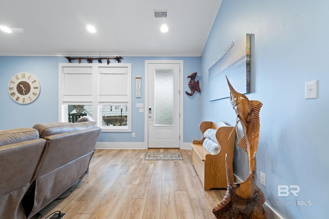 entrance foyer featuring crown molding, a wealth of natural light, and light hardwood / wood-style floors