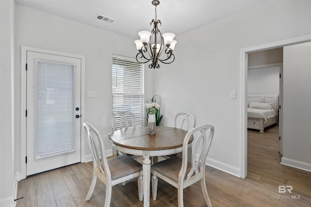 dining area with light wood finished floors, a notable chandelier, baseboards, and visible vents