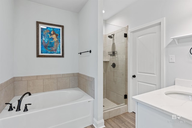 bathroom with vanity, a shower stall, a bath, and wood finished floors