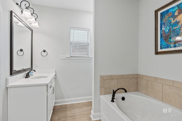 full bath with baseboards, vanity, a bath, and wood finished floors