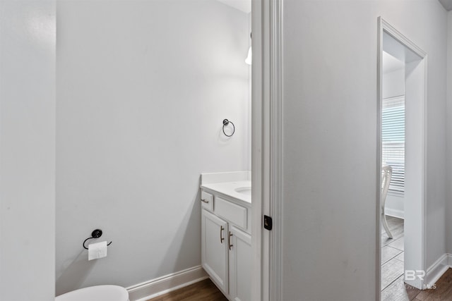 bathroom featuring vanity, toilet, baseboards, and wood finished floors