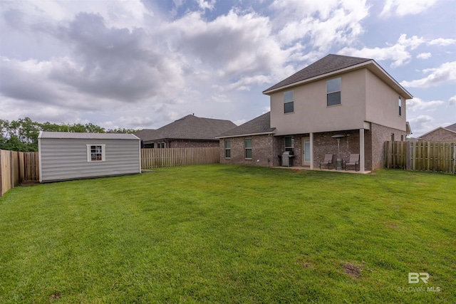 back of house featuring a fenced backyard, an outdoor structure, a yard, and brick siding